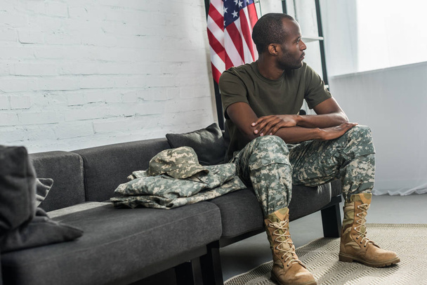 Красивый солдат-мужчина сидит на диване в камуфляжной одежде
 - Фото, изображение