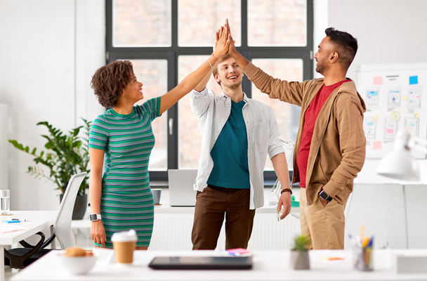 happy creative team making high five at office - Photo, Image