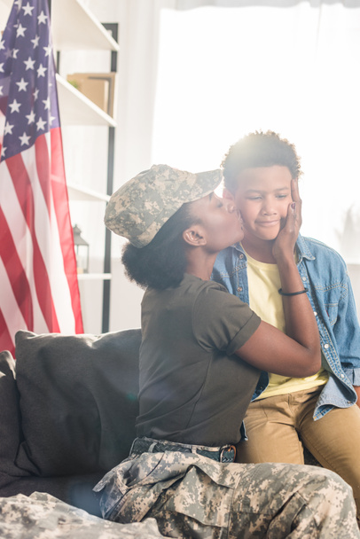 Female soldier in camouflage clothes kissing her son - Photo, Image