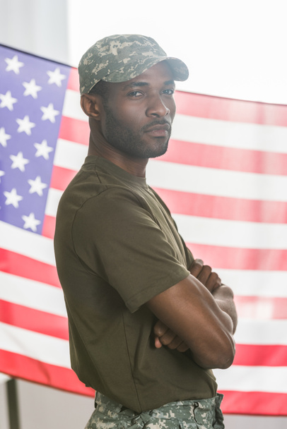 Confident african american man in camouflage clothes in front of us flag - 写真・画像