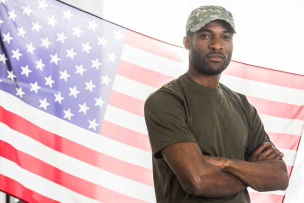 Handsome african american soldier in camouflage clothes in front of us flag - Foto, afbeelding