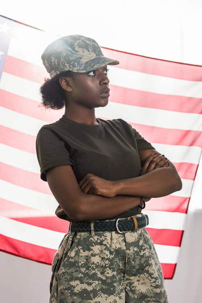 Young african american female soldier in camouflage clothes in front of us flag - Φωτογραφία, εικόνα
