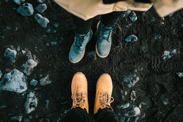Couple in a hiking boots stand on black sand. Iceland. Top view - Valokuva, kuva
