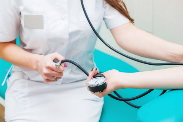 Close up view of female medicine doctor measuring blood pressure to her patient. Hands close up. Healthcare, healthy lifestyle and medical service concept - Photo, image