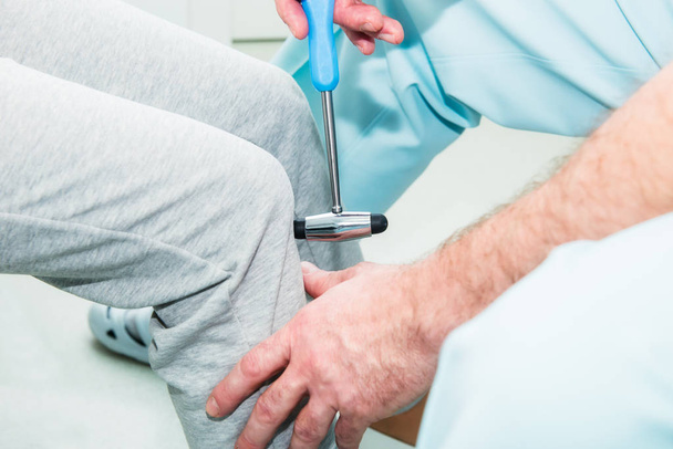The neurologist testing knee reflex on a female patient using a hammer. Neurological physical examination. Selective focus, close up. - Foto, Imagem