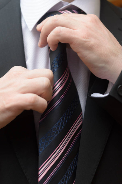 Empresario en un traje de negocios endereza su corbata
. - Foto, imagen