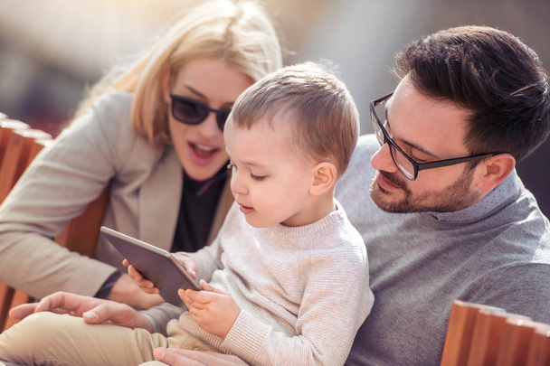 Familia feliz divirtiéndose al aire libre con tableta
. - Foto, Imagen