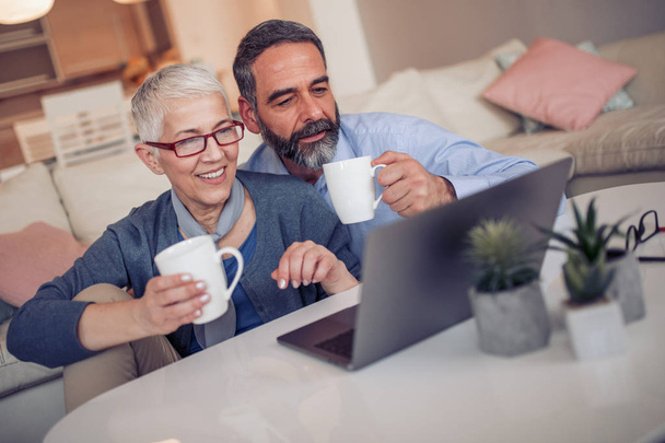 Senior couple working with laptop at home. - Zdjęcie, obraz