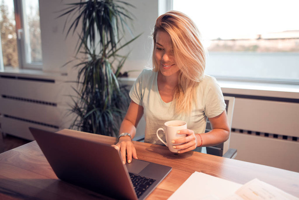 Mujer joven atractiva usando el ordenador portátil y trabajando en las finanzas en casa
. - Foto, Imagen