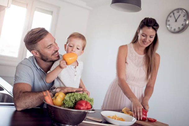 glückliche Familie bereitet zu Hause in der Küche gemeinsam Gemüse zu. - Foto, Bild