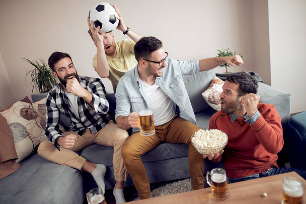 Groupe d'amis regardant le match de football à la télévision, célébrer le but
. - Photo, image