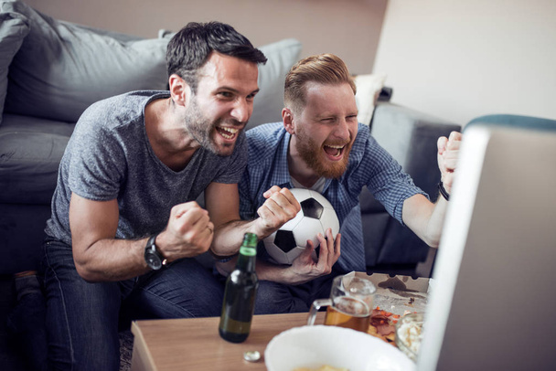 Happy male friends watching soccer on tv at home. - Φωτογραφία, εικόνα