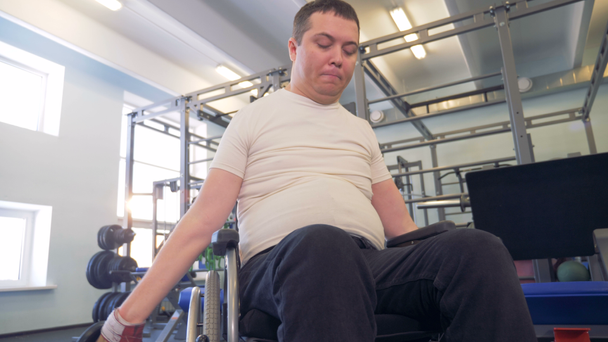 Disabled athlete in a wheelchair strengths his hands via dumbbells. - Πλάνα, βίντεο