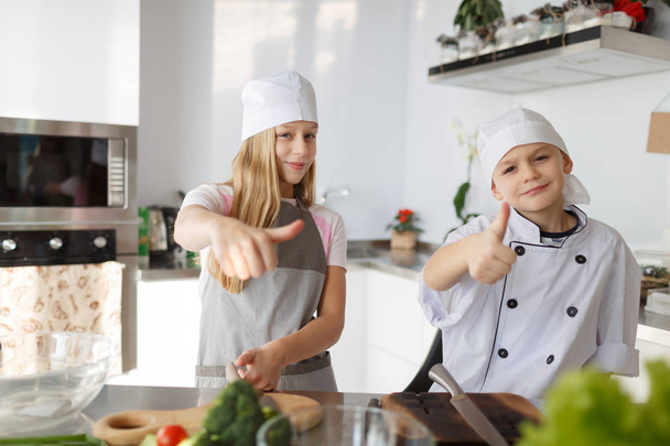 A brother and a sister cooking a healthy dish from broccoli and other vegetables in the kitchen room. Organic food for family dinner concept. - Foto, imagen