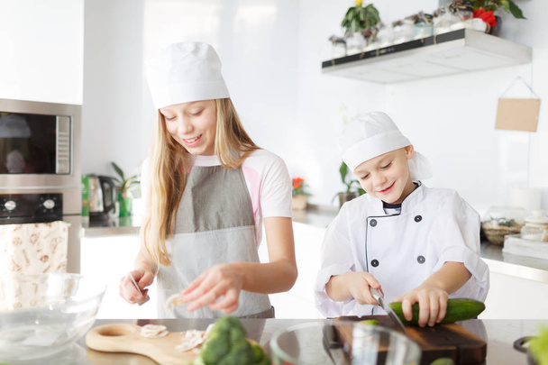 A brother and a sister cutting  vegetables  in the modern kitchen room. Happy family cooking concept. - Фото, зображення