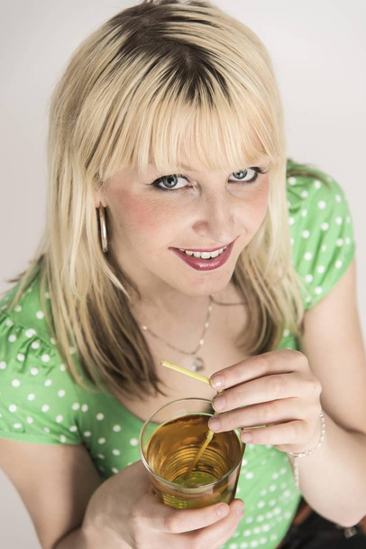 Young woman with a glass of apple juice with a drinking straw in front of her - Foto, Bild