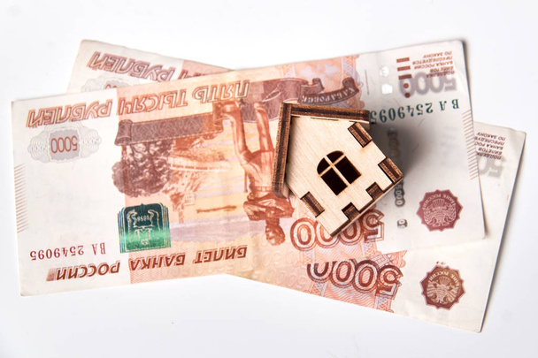 Russische Rubel-Banknoten unter Haus. / Währung, zum Verkauf, Haus, Hypothekendokument, Umzugshaus - Foto, Bild
