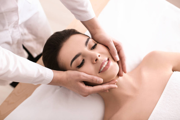 Mujer joven disfrutando de masajes faciales en el salón de spa
 - Foto, Imagen