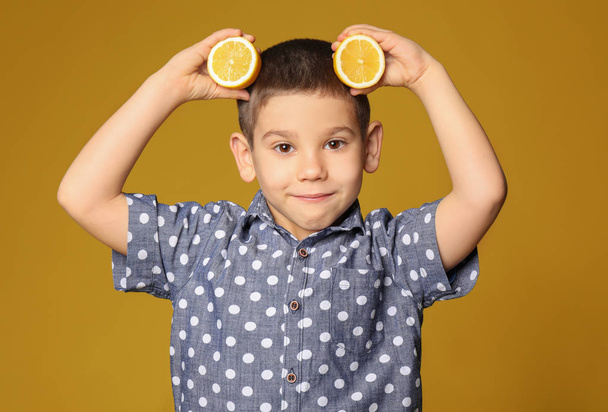 Funny little boy with citrus fruit on color background - Foto, Imagen