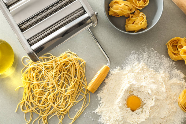 Flat lay composition with metal pasta maker and products on light background - Foto, imagen
