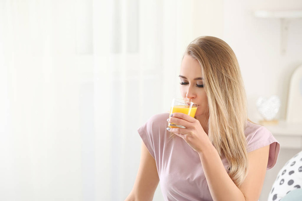 Beautiful young woman drinking citrus juice at home - Фото, изображение