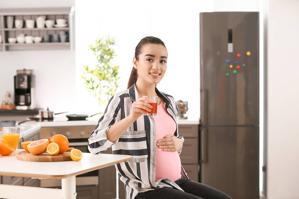 Bella donna incinta che beve succo di agrumi a casa
 - Foto, immagini