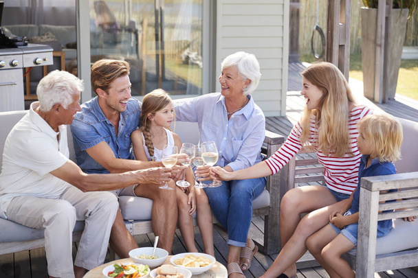 Multi Generation Family Enjoy Outdoor Drinks And Snacks At Home - Foto, Imagen