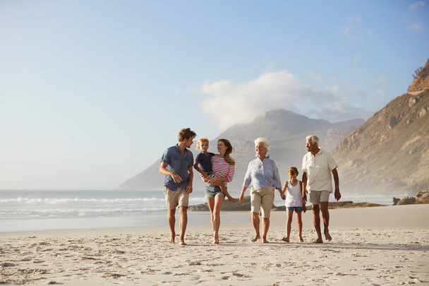 Multi Generation Family On Vacation Walking Along Beach Together - Foto, imagen