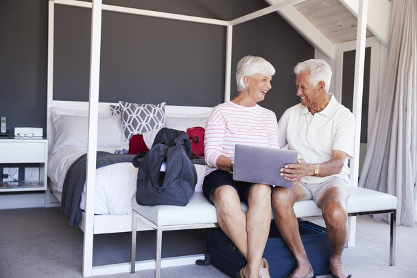 Senior Couple Look At Laptop As They Check In To Vacation Rental - Photo, image