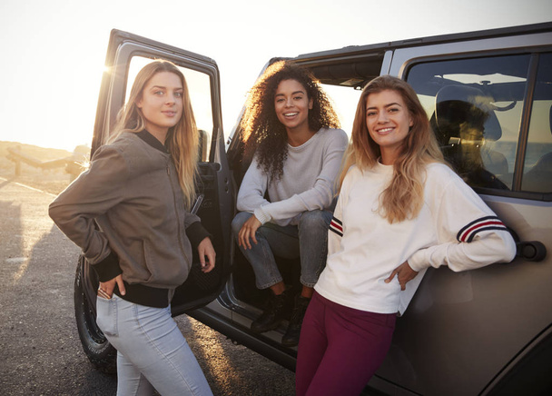 Three female friends on road trip looking at camera from car - Zdjęcie, obraz