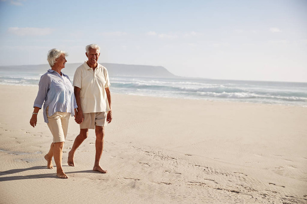 Sénior aposentado casal andando ao longo praia mão na mão juntos
 - Foto, Imagem