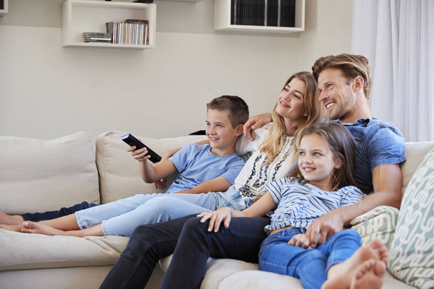 Family Sitting On Sofa At Home Watching TV Together - Фото, изображение
