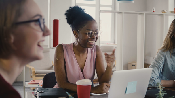 Happy afroamerické zaměstnaná žena sedí u stolu na schůzi týmu. Mnohonárodnostní týmová práce v moderní kanceláři 4k. - Záběry, video