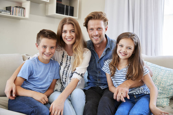 Portrait Of Smiling Family Sitting On Sofa At Home Together - Foto, afbeelding