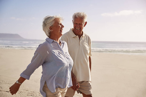 Ανώτερος συνταξιούχος ζευγάρι περπάτημα κατά μήκος της παραλίας, χέρι-χέρι μαζί - Φωτογραφία, εικόνα