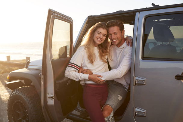 Young white couple on a road trip embracing by their car - Foto, Imagen
