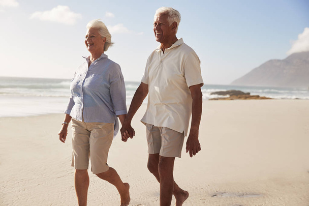 Sénior aposentado casal andando ao longo praia mão na mão juntos
 - Foto, Imagem