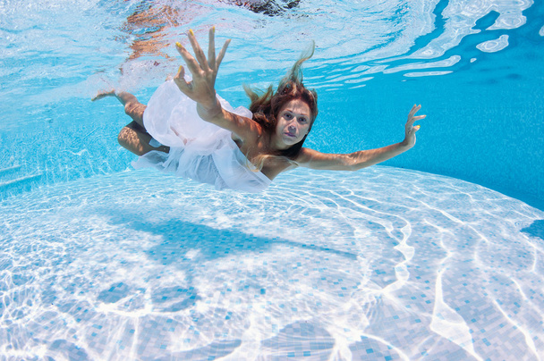 Underwater woman fashion portrait with white dress in swimming pool - 写真・画像