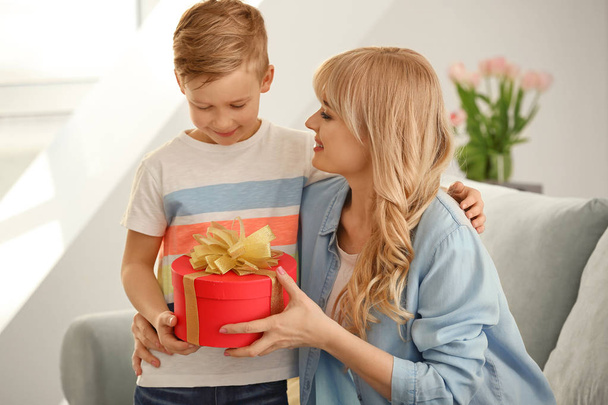 Portrait of cute little boy and his mother with gift box at home - Foto, immagini