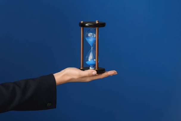 Woman holding hourglass on color background. Time management concept - Fotografie, Obrázek