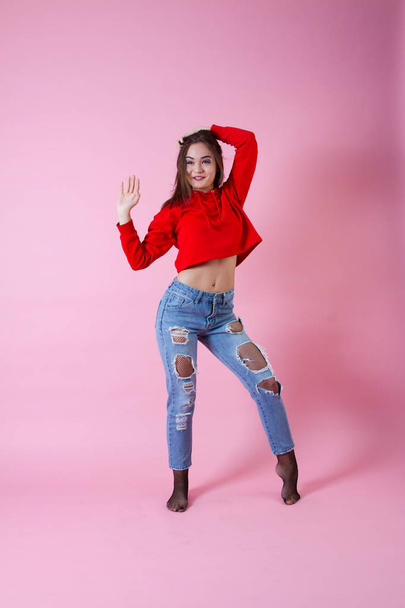 Emotional girl in jeans and a red sweater. Studio portrait - Photo, Image