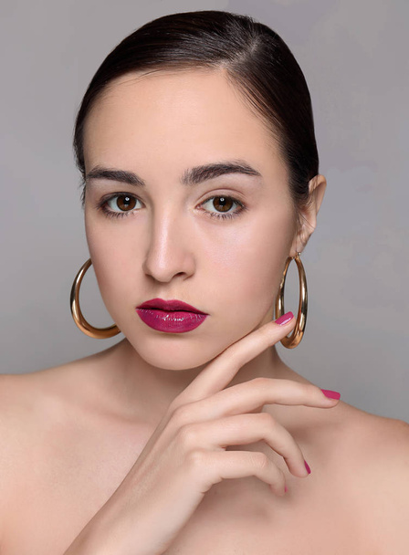 Portrait de jeune femme avec un beau maquillage professionnel sur fond gris
 - Photo, image