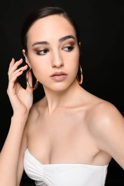 Portrait of young woman with beautiful professional makeup on black background - 写真・画像