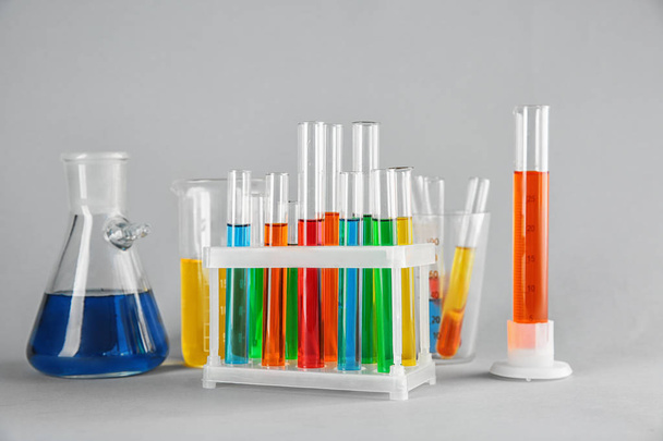 Chemische glaswerk met kleurrijke monsters op kleur achtergrond - Foto, afbeelding