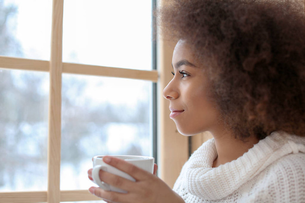 Belle femme afro-américaine buvant du thé près de la fenêtre
 - Photo, image
