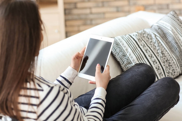 junge Frau benutzt Tablet, während sie zu Hause auf dem Sofa liegt - Foto, Bild