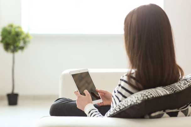 Молода жінка використовує планшет під час відпочинку на дивані вдома
 - Фото, зображення