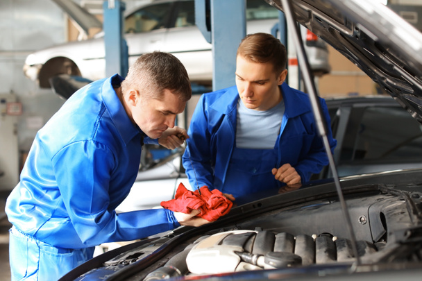 Male mechanics fixing car in service center - Foto, afbeelding