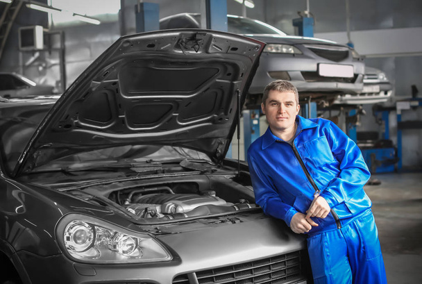 Portrait of male mechanic near car in service center - Foto, afbeelding