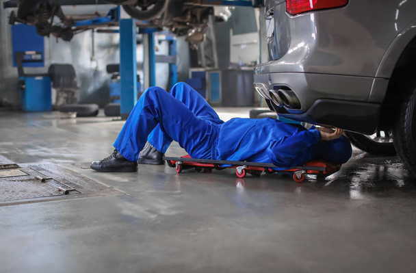 Male mechanic fixing car in service center - Photo, image
